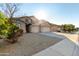 Tan three-car garage home with desert landscaping and tree at 43205 W Askew Dr, Maricopa, AZ 85138