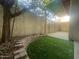 Enclosed patio area with retaining wall, artificial turf, mature tree, and covered area at 910 N Center St # 24, Mesa, AZ 85201