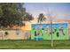 Community dog park with a mural wall, green lawn, and mature trees at sunset at 17200 W Bell Rd # 1015, Surprise, AZ 85374