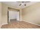 Cozy bedroom features light hardwood flooring, a ceiling fan, and a spacious closet with double doors at 12121 W Patrick Ln, Sun City, AZ 85373