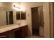 Bathroom with dual sinks, large mirror, and walk-in closet with glass doors at 14543 W Bison Path, Surprise, AZ 85374