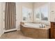 A modern bathroom showcasing a soaking tub under two windows with plantation shutters at 21774 E Camacho Rd, Queen Creek, AZ 85142