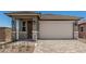 Charming single-Gathering home featuring a front door, two-car garage, and a well-maintained, professionally-designed paver driveway at 5649 N 205Th Ln, Buckeye, AZ 85396