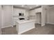 Bright kitchen with stainless steel microwave, white cabinets, and a large island with sink at 5649 N 205Th Ln, Buckeye, AZ 85396