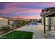 Twilit backyard view showcasing a pool, travertine patio, and string lights at 4779 N 205Th Gln, Buckeye, AZ 85396
