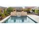 Elegant pool featuring a stone waterfall feature and lush surrounding greenery under a clear sky at 4779 N 205Th Gln, Buckeye, AZ 85396