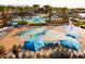 Resort-style community pool area with splash pad, lounge chairs, umbrellas, and palm trees for a relaxing outdoor experience at 20105 W Campbell Ave, Buckeye, AZ 85396