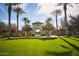 Picturesque entrance to Founders Park featuring an arched entryway, lush green lawn and mature palm trees on a sunny day at 20105 W Campbell Ave, Buckeye, AZ 85396