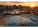 Community pool area with lounge chairs, umbrellas, and palm trees during a golden sunset at 20105 W Campbell Ave, Buckeye, AZ 85396