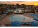 Community pool area with lounge chairs, umbrellas, and palm trees creating a relaxing atmosphere at sunset at 20105 W Campbell Ave, Buckeye, AZ 85396