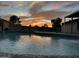 A tranquil swimming pool reflects a dramatic sunset, surrounded by seating areas for relaxation and entertainment at 5625 W Grovers Ave, Glendale, AZ 85308