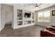 Inviting living room featuring a built-in entertainment center, ceiling fan, and wood-look flooring at 26783 W Zachary Dr, Buckeye, AZ 85396