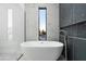 Bathroom with a freestanding tub, a large window, and dark gray tiles at 6338 N 10Th Dr, Phoenix, AZ 85013