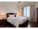A cozy bedroom with a dark wood bed frame, bedside tables with lamps, and hardwood floors at 6322 E Turquoise Ave, Paradise Valley, AZ 85253