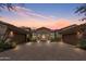 Beautiful stone home exterior with a three car garage and a well-manicured front yard under a colorful sunset at 6322 E Turquoise Ave, Paradise Valley, AZ 85253
