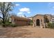 Beautiful stone home exterior with three car garage, arched doorway, and mature landscaping at 6322 E Turquoise Ave, Paradise Valley, AZ 85253