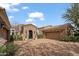 View of home exterior with a stone facade, three-car garage, arched entryway and mature landscaping at 6322 E Turquoise Ave, Paradise Valley, AZ 85253