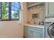 Well-lit laundry room featuring a sink, cabinet, stone tile backsplash and a modern washing machine at 6322 E Turquoise Ave, Paradise Valley, AZ 85253