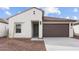 Inviting facade of a modern residence featuring a stucco exterior, dark brown garage door, and drought-tolerant landscaping at 23411 W Albeniz Pl, Buckeye, AZ 85326