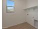 A laundry room with wood-look vinyl flooring, a window with a view, and white shelving at 34505 N Timberlake N Mnr, San Tan Valley, AZ 85144
