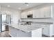 A modern kitchen with a large island, granite countertops, stainless steel appliances, and white cabinetry at 8975 S 168Th Ln, Goodyear, AZ 85338