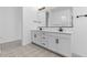 Modern double vanity bathroom with white cabinets and patterned floors at 37767 W Padilla St, Maricopa, AZ 85138