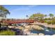 Scenic view of a red pedestrian bridge spanning a stream in a well-maintained community, featuring palm trees and landscaping at 17915 W Silver Fox Way, Goodyear, AZ 85338