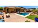 Expansive backyard featuring a sparkling pool, patio seating, and lush green landscaping at 18174 W Wind Song Ave, Goodyear, AZ 85338