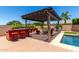 Outdoor bar and lounge area in backyard, situated under a pergola, near the inviting pool at 18174 W Wind Song Ave, Goodyear, AZ 85338