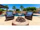 Inviting backyard oasis with a fire pit and comfortable seating by the refreshing pool and lush palm trees at 18174 W Wind Song Ave, Goodyear, AZ 85338