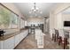 Well-lit kitchen with white cabinets, stainless steel appliances, a center island, and an open bar seating area at 18174 W Wind Song Ave, Goodyear, AZ 85338