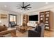 Inviting living room with wood floors, a ceiling fan, built-in shelving and comfortable seating arrangements at 18450 W Elwood St, Goodyear, AZ 85338