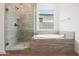 Elegant bathroom showcasing a modern shower with glass door and a soaking tub with tiled surround at 44713 N 44Th Dr, Phoenix, AZ 85087