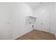 Bright laundry room featuring white walls, tile floors, utility sink, and convenient shelving at 44713 N 44Th Dr, Phoenix, AZ 85087