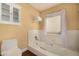 Clean bathroom with a white tub, a window, and a matching toilet at 629 E Myrtle Ave, Phoenix, AZ 85020