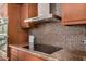 Modern kitchen with stainless steel range hood, cooktop, stylish backsplash, and sleek cabinets at 629 E Myrtle Ave, Phoenix, AZ 85020