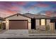 A single story home with a two-car garage, stone accents and a beautiful sunset at 16032 W Desert Hollow Dr, Surprise, AZ 85387