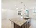 A kitchen island with a granite countertop and stainless steel sink anchors this modern, open kitchen design at 16032 W Desert Hollow Dr, Surprise, AZ 85387