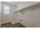Empty laundry room with bright window, open shelving, tile flooring, and connections for machines at 3247 W Garnet St, San Tan Valley, AZ 85144