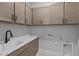 Well-lit laundry room features cabinets for storage, counter space, a sink and modern fixtures at 32994 N 131St Dr, Peoria, AZ 85383