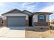 Charming single-Gathering home featuring stone accents, a gray garage door, and desert landscaping at 8584 N 170Th Ln, Waddell, AZ 85355