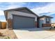 Single-Gathering home featuring stone accents, a gray garage door, drought-tolerant landscaping and large driveway at 8584 N 170Th Ln, Waddell, AZ 85355