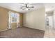A carpeted bedroom featuring a ceiling fan, large window, and a view of the hallway leading to the closet at 1335 E June St # 239, Mesa, AZ 85203