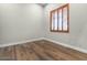 Bare bedroom with hardwood-style flooring, baseboards, and a shuttered window at 2121 N Orchard --, Mesa, AZ 85213