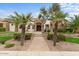 Stunning home exterior featuring a stone archway, manicured lawn, and mature palm trees, creating curb appeal at 2121 N Orchard --, Mesa, AZ 85213