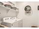 Well-lit laundry room equipped with washer, dryer, and decorative wall shelving at 4488 W Charlie Dr, San Tan Valley, AZ 85144