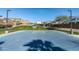 Outdoor basketball court with a blue surface, white lines, and basketball hoop surrounded by landscaping and blue sky at 634 E Deer Creek Rd, Phoenix, AZ 85048