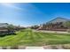 Community greenbelt with lush grass, landscaping, retaining walls, and homes in the background under a blue sky at 634 E Deer Creek Rd, Phoenix, AZ 85048