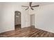 Bedroom featuring wood-look floors, ceiling fan, and arched doorway to bathroom at 8549 W El Caminito Dr, Peoria, AZ 85345