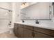 Bathroom featuring dual vanity with contemporary fixtures, large mirror, and a shower/tub combo at 17586 W Blue Sky Dr, Surprise, AZ 85387